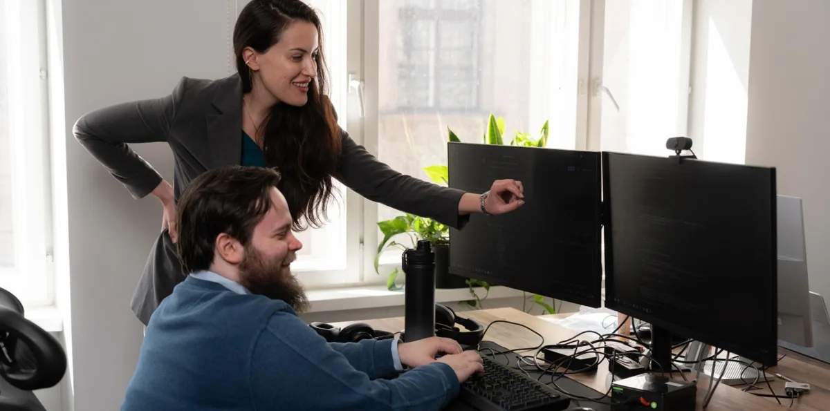 eCommerce manager pointing at store data on a colleague's monitors during a review